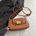 Brown leather saddle shoulder bag featuring a unique gold chocolate-shaped metal buckle clasp - Brown