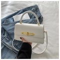Detalle de bolso de mano blanco con cierre dorado sobre una chaqueta vaquera azul - Blanco