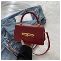 Detalle de un bolso bandolera de cuero burdeos con hebilla dorada y asa superior - Rojo