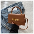 Detail of a brown leather crossbody bag with a gold metal bar buckle and rounded handle - Brown