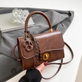 Vintage dark brown textured crossbody bag with golden ring lock and woven strap detail - Brown with Pendant