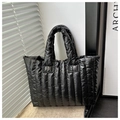 Detail of black quilted down tote bag with glossy finish and vertical stitching detail - Black