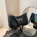 Elegant black crocodile-pattern shoulder bag with a gold bow buckle on a warm indoor backdrop - Crocodile Pattern Black