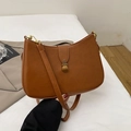 Bolso hobo marrón de cuero sintético con hebilla dorada sobre tela blanca elegante - Marrón