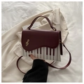 Détail du sac motif touches de piano avec boucle clé de sol dorée et rabat rouge - Rouge