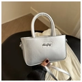 Silberne Metallic-Handtasche mit Riemen in der Hand zur Darstellung der Proportionen - Silber