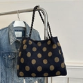 Borsa tote blu scuro a pois marroni con manici intrecciati neri appesa a un appendiabiti - Cachi