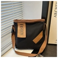Detalle de bolso tote de lona con correas de cuero marrón y etiqueta de moda en luz suave - Negro