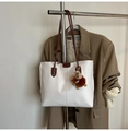 Detalle del bolso tote blanco con correas de cuero marrón y un colgante de peluche - Con Colgante / Blanco