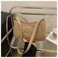 Detalle de bolso medialuna beige con hebilla de lazo dorado y costuras de alta calidad - Caqui