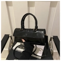 Detalle del bolso cuadrado pequeño de charol negro con acabado brillante y herrajes dorados - Negro