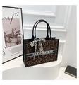 Detailopname van luipaardprint shopper met zwarte leren handvatten en zijden strik - Bruin