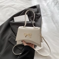 Elegant cream-white crossbody bag featuring a golden bow detail and curved base - White