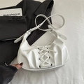 White PU leather crescent bag with bow ties and silver eyelets shown in lifestyle setting - White