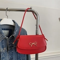 Rote Leder-Satteltasche mit goldener Schleife vor blauem Denim-Hintergrund - Rot