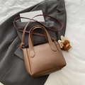 Brown litchi grain leather bucket bag with top handles and slender shoulder strap - Brown with Pendant