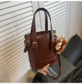 Detail der dunkelbraunen Eimer-Tasche mit goldener Hardware und Plüschtier-Anhänger - Kaffeebraun (Mit Anhänger)