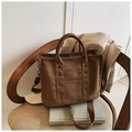 Detail view of large canvas tote bag with decorative rivets on a wooden chair - Dark Brown