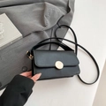 Borsa a mano minimalista in pelle nera con fibbia circolare dorata su giacca grigia - Nero