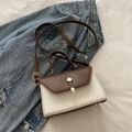Bolso de mano vintage en color marrón y crema con hebilla dorada sobre fondo de mezclilla - Marrón