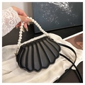 Detail van zwarte schelpvormige tas met parelhandvat op witte zijden stof achtergrond - Zwart