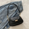 Sleek black shoulder bag with golden spiral clasp and metallic chain detail on blue denim - Black