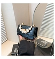 Close-up of black crocodile pattern leather bag with pearl handle and gold chain strap - Black