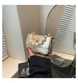 Macro detail of gold crocodile-embossed mini bag with pearl handle and metal lock - Gold