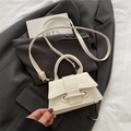 Schicke weiße Handtasche mit Marmorstruktur und goldenen Details auf grauem Sakko - Weiß