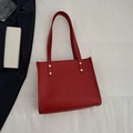 Minimalist red leather tote bag with gold rivets on elegant white fabric background - Red