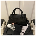 Detalle de bolso negro con patrón de cocodrilo, texto dorado y asa superior fija - Negro