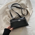 Bolso caja retro de cuero negro brillante con bandolera sobre un blazer beige - Negro