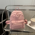 Minimalist pink corduroy mini backpack with front zipper pocket on metal shelf - Pink