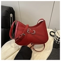 Close-up of red leather underarm bag featuring vintage silver buckles and a biker style - Red