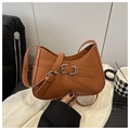 Close-up of caramel leather shoulder bag with decorative strap and metallic buckle detail - Brown