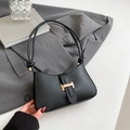 Minimalist black baguette bag with gold H-buckle and knotted strap on gray blazer - Black