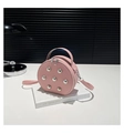 Détail du sac rond rose à rivets sur livre blanc avec fermeture éclair double élégante - Rose