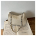 Dettaglio borsa beige intrecciata con catena argento su un libro vintage - Cachi