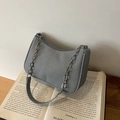 Borsa hobo grigia testurizzata con catena argento e tracolla sottile su libro vintage - Blu