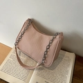 Borsa a tracolla rosa cipria testurizzata con catena su un tavolo in legno - Rosa