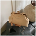 Detail of beige woven texture bag with gold hardware and metal ring handle on book - Khaki