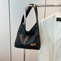 Borsa tote nera minimalista con etichetta marrone appesa a una rastrelliera metallica - Nero