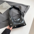 Glossy black crescent shoulder bag with silver rivet studs in a minimalist setting - Black