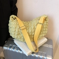 Light yellow popcorn textured crossbody bag with adjustable wide fabric strap on a suitcase - Yellow