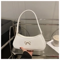 Nahaufnahme einer weißen Halbmond-Tasche mit goldener Metallschleife auf Lederfläche - Weiß