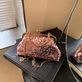 Elegante rosa Pailletten-Abendtasche mit goldener Kette auf einem Vintage-Buch - Rosa