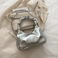 Borsa a mano argento metallizzato con pieghe, catena e perle su un abito beige - Senza Ciondolo / Argento