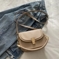 Retro cremefarbene Umhängetasche in Sattelform mit Goldschnalle auf blauem Denim - Khaki