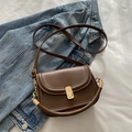 Deep brown matte leather saddle bag with gold metal clasp on denim background - Brown