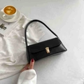 Schwarze Baguette-Tasche mit goldener Metallschnalle auf weißem strukturiertem Stoff - Schwarz